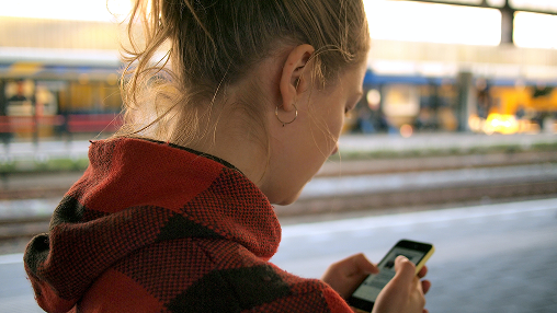 Mulher usando celular na estação